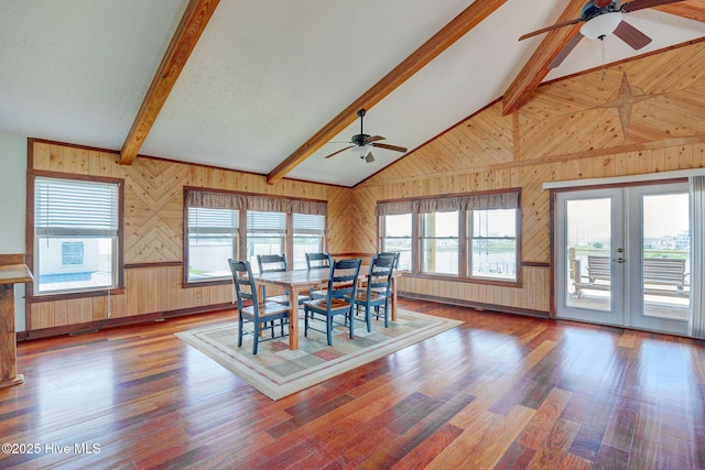 dining space with ceiling fan, wood walls, wood finished floors, and french doors