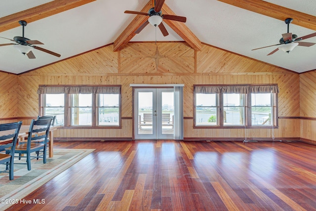 living area with a ceiling fan, wooden walls, wood finished floors, and french doors