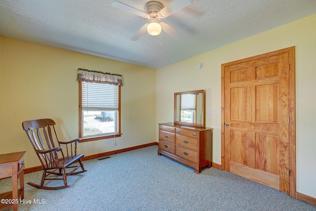 living area with plenty of natural light, carpet flooring, baseboards, and a textured ceiling