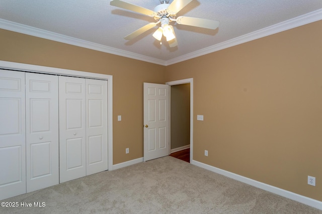 unfurnished bedroom featuring carpet floors, ornamental molding, a closet, baseboards, and ceiling fan