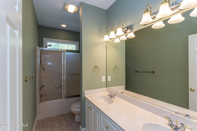 bathroom featuring a sink, double vanity, toilet, tile patterned floors, and bath / shower combo with glass door