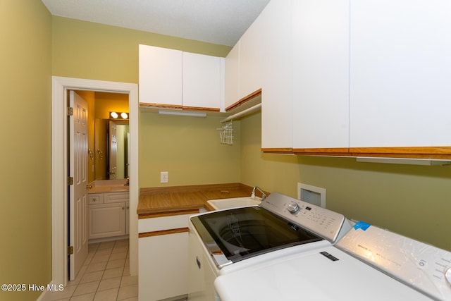 clothes washing area with washing machine and clothes dryer, light tile patterned floors, a sink, and cabinet space