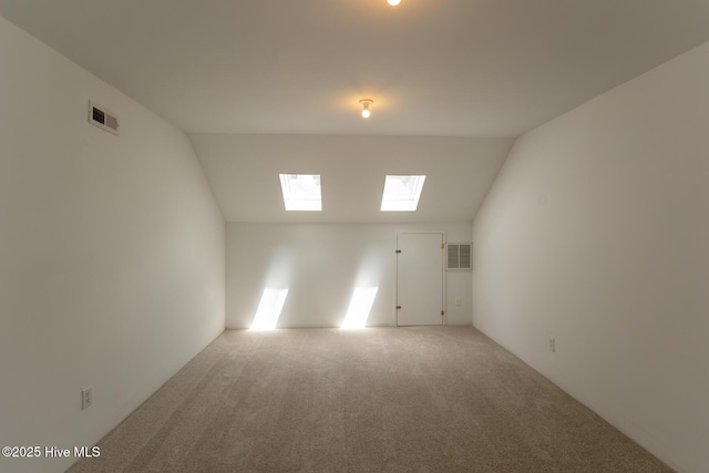spare room with light carpet, lofted ceiling with skylight, and visible vents