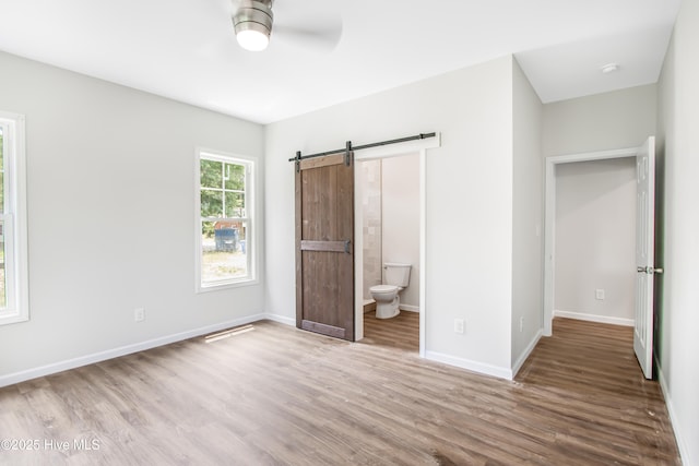 401 Singletary St SE, Wilson, NC 27893 - unfurnished bedroom with a barn door, wood finished floors, baseboards, and ensuite bath