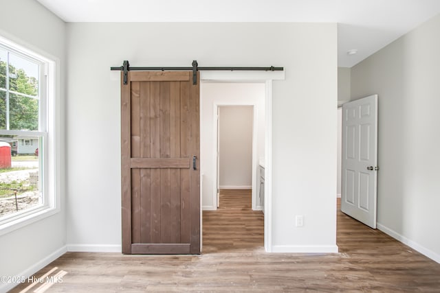 401 Singletary St SE, Wilson, NC 27893 - unfurnished bedroom with wood finished floors, baseboards, and a barn door