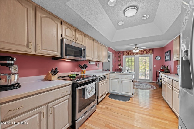 kitchen with light wood-type flooring, a peninsula, a textured ceiling, and appliances with stainless steel finishes