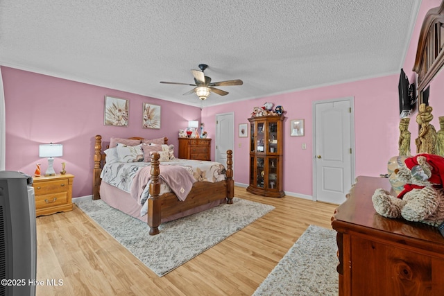 bedroom featuring baseboards, a textured ceiling, light wood finished floors, and ceiling fan
