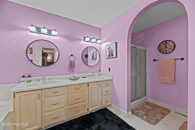 full bath featuring double vanity, a sink, tile patterned flooring, and a stall shower