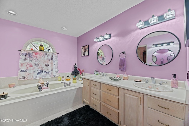 bathroom with double vanity, tile patterned flooring, a sink, and a garden tub