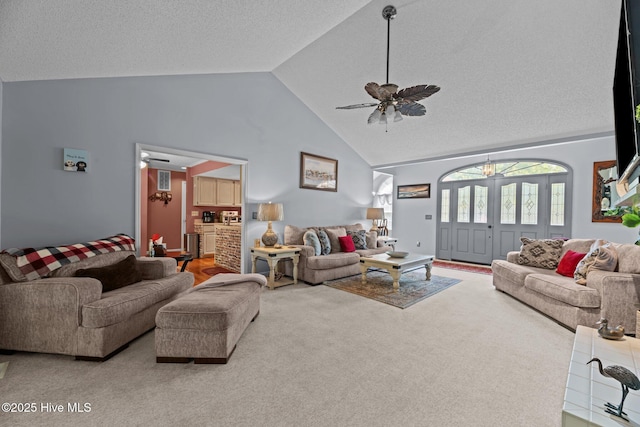 carpeted living room featuring a ceiling fan, high vaulted ceiling, and a textured ceiling