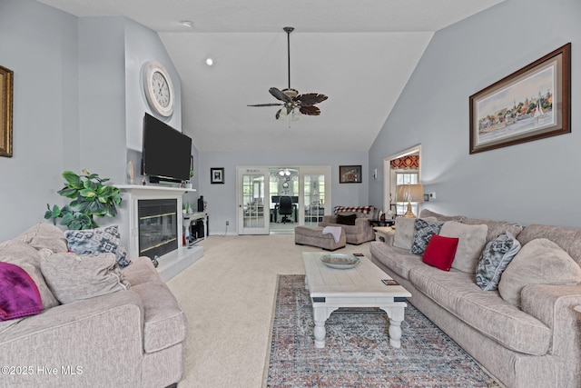 carpeted living room featuring a ceiling fan, high vaulted ceiling, a glass covered fireplace, and french doors