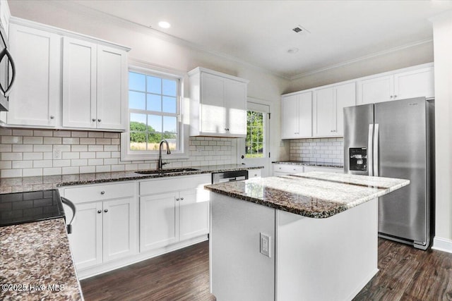 kitchen with a kitchen island, stainless steel refrigerator with ice dispenser, dark stone countertops, dark wood-style floors, and white cabinetry