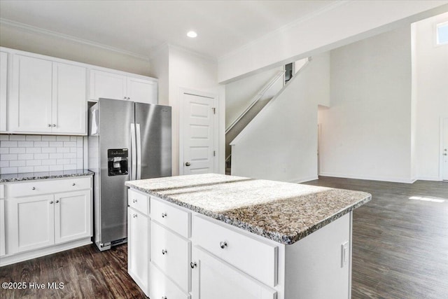 kitchen featuring stainless steel fridge, ornamental molding, light stone countertops, and a center island