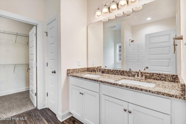 full bath with a sink, a walk in closet, a shower, and wood finished floors
