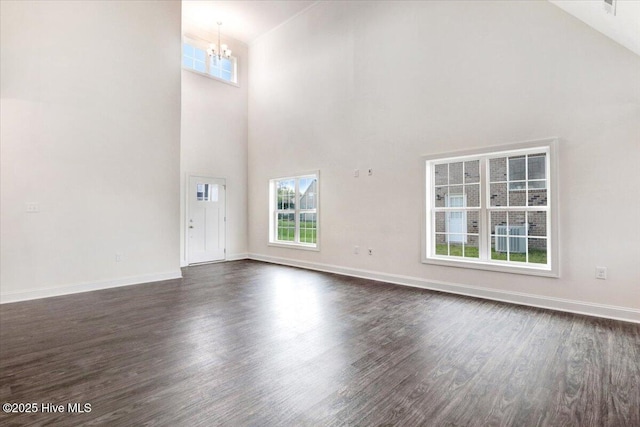 unfurnished living room featuring an inviting chandelier, high vaulted ceiling, and dark wood-style flooring