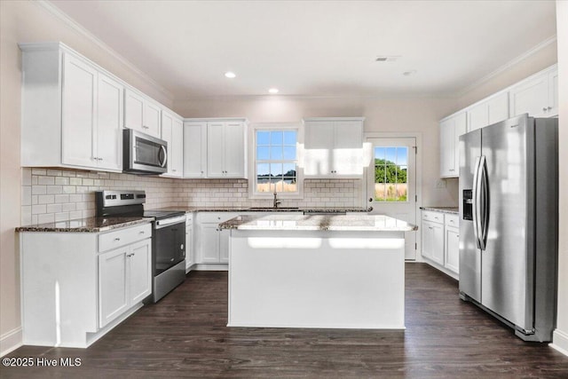 kitchen with white cabinets, a center island, stainless steel appliances, stone counters, and backsplash