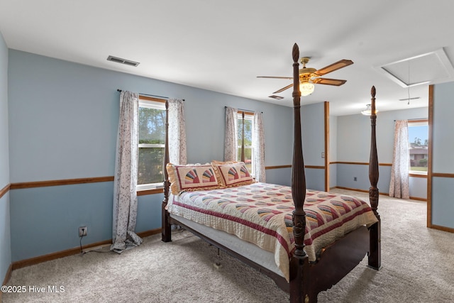 carpeted bedroom featuring visible vents, attic access, baseboards, and a ceiling fan
