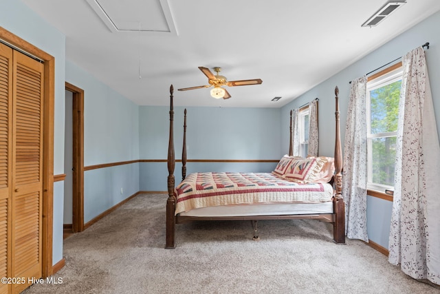 carpeted bedroom with a ceiling fan, baseboards, visible vents, and attic access