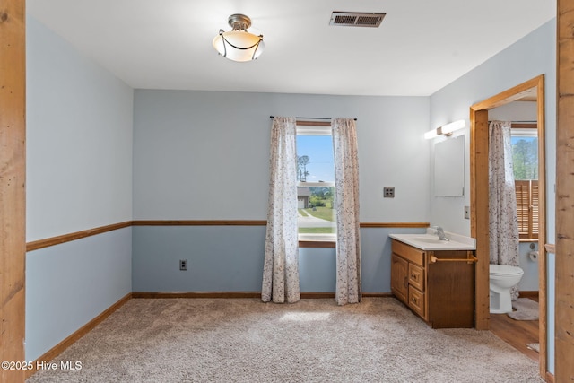 unfurnished bedroom with light colored carpet, baseboards, visible vents, and a sink