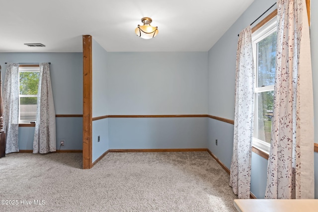 carpeted empty room featuring baseboards and visible vents