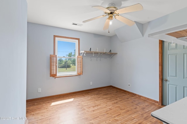 empty room with visible vents, light wood finished floors, ceiling fan, and baseboards