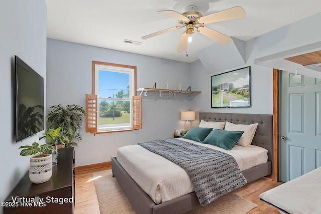 bedroom featuring a ceiling fan, visible vents, and wood finished floors