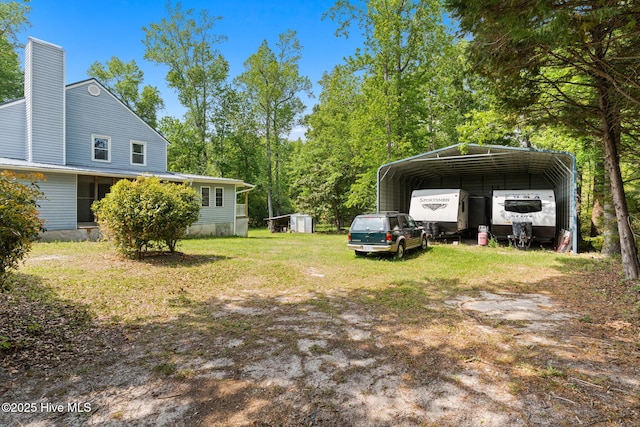 view of yard with a storage unit, a carport, an outdoor structure, and driveway