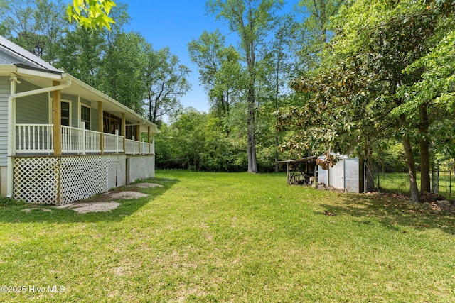 view of yard with a storage unit, fence, an outbuilding, and a porch