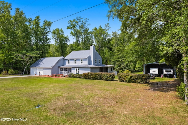 view of front of home featuring a chimney, a detached carport, driveway, and a front yard