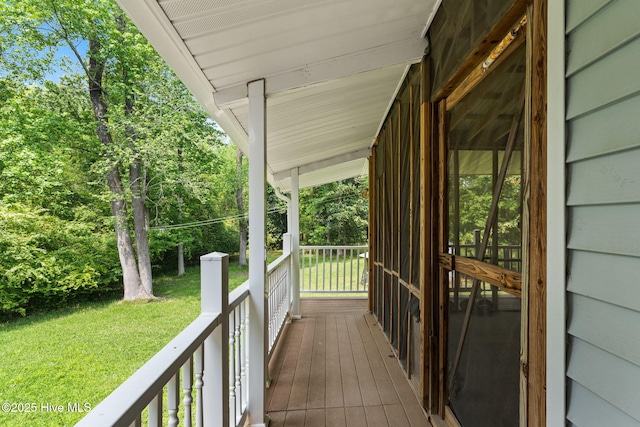 wooden terrace featuring covered porch and a yard
