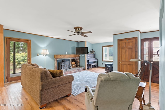 living room featuring ceiling fan, plenty of natural light, ornamental molding, and light wood-style flooring