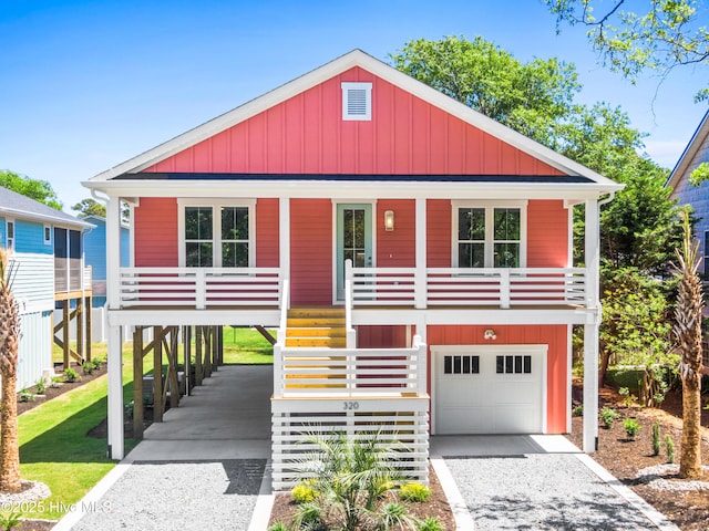 raised beach house with a garage, board and batten siding, a porch, stairway, and driveway