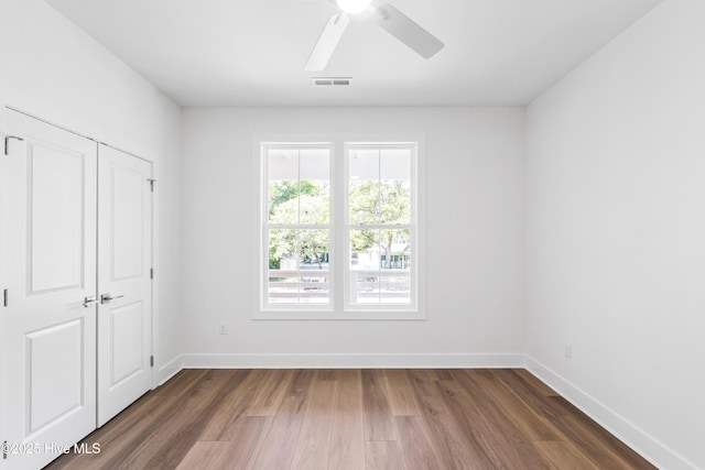 unfurnished bedroom with baseboards, a closet, wood finished floors, and visible vents