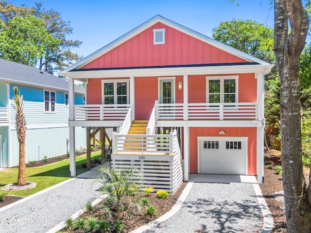 coastal home with board and batten siding, stairs, a porch, and gravel driveway