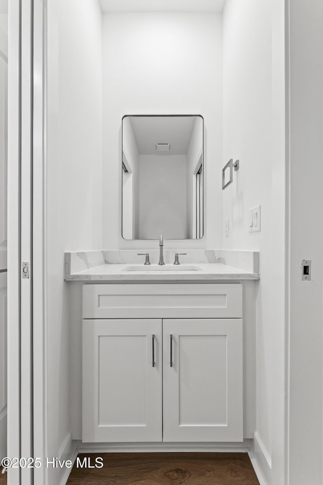 bathroom featuring vanity, baseboards, wood finished floors, and visible vents