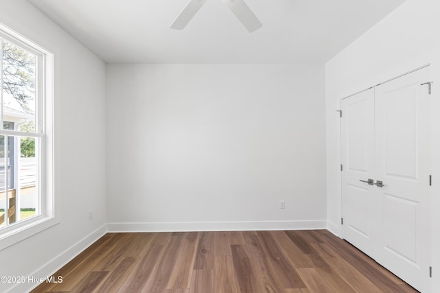unfurnished bedroom featuring baseboards, a ceiling fan, wood finished floors, and a closet