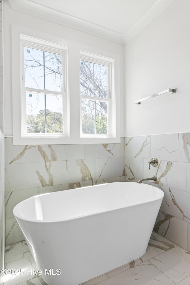 bathroom with a freestanding tub, tile walls, wainscoting, and marble finish floor