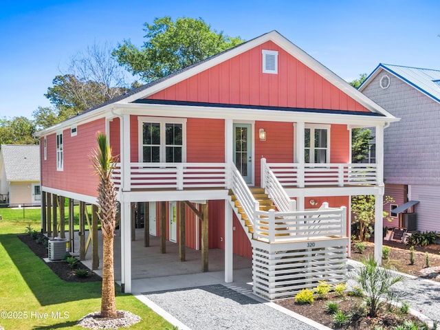 coastal inspired home featuring board and batten siding, a porch, stairway, a carport, and driveway