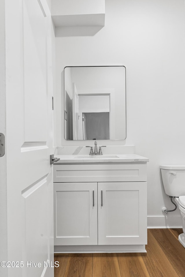 bathroom with vanity, baseboards, toilet, and wood finished floors