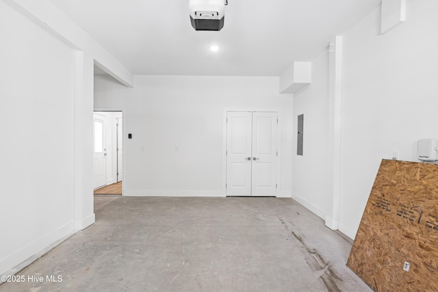 unfurnished room featuring baseboards, unfinished concrete floors, and electric panel