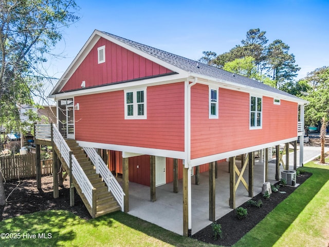 rear view of house with fence, stairs, a shingled roof, central AC unit, and a carport