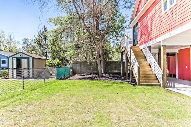 view of yard with a fenced backyard, an outbuilding, stairs, and a shed