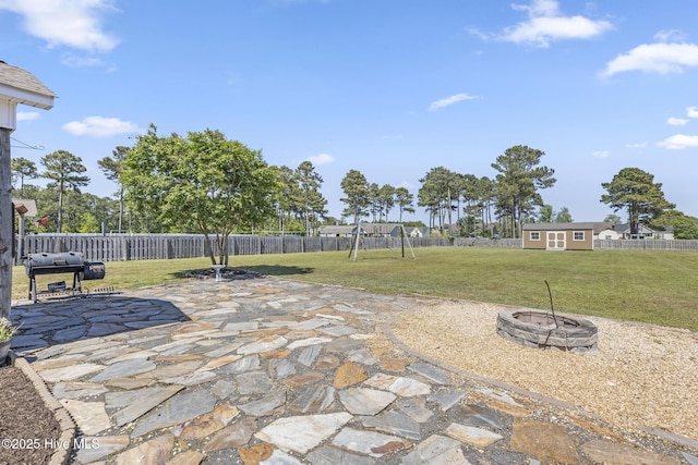 view of patio / terrace with an outdoor fire pit, area for grilling, a fenced backyard, a playground, and an outdoor structure