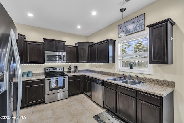 kitchen with pendant lighting, recessed lighting, light countertops, a sink, and stainless steel appliances