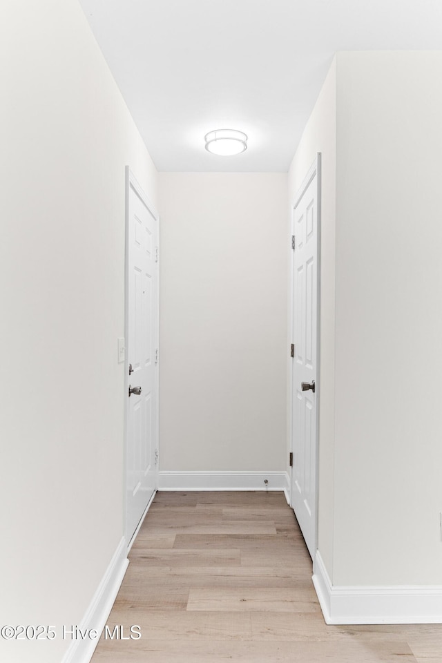 corridor featuring light wood-type flooring and baseboards