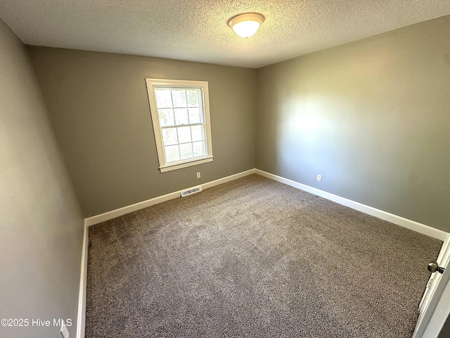 carpeted spare room featuring a textured ceiling, visible vents, and baseboards