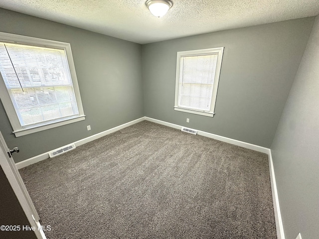 spare room featuring visible vents, a textured ceiling, and a healthy amount of sunlight