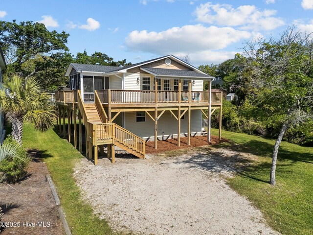 rear view of house with a deck, a sunroom, a yard, a shingled roof, and stairs