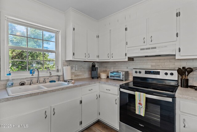 kitchen featuring electric range, a sink, light countertops, decorative backsplash, and under cabinet range hood