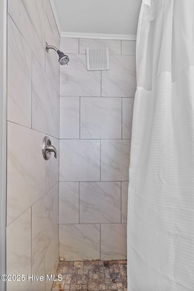 full bathroom featuring ornamental molding and a tile shower